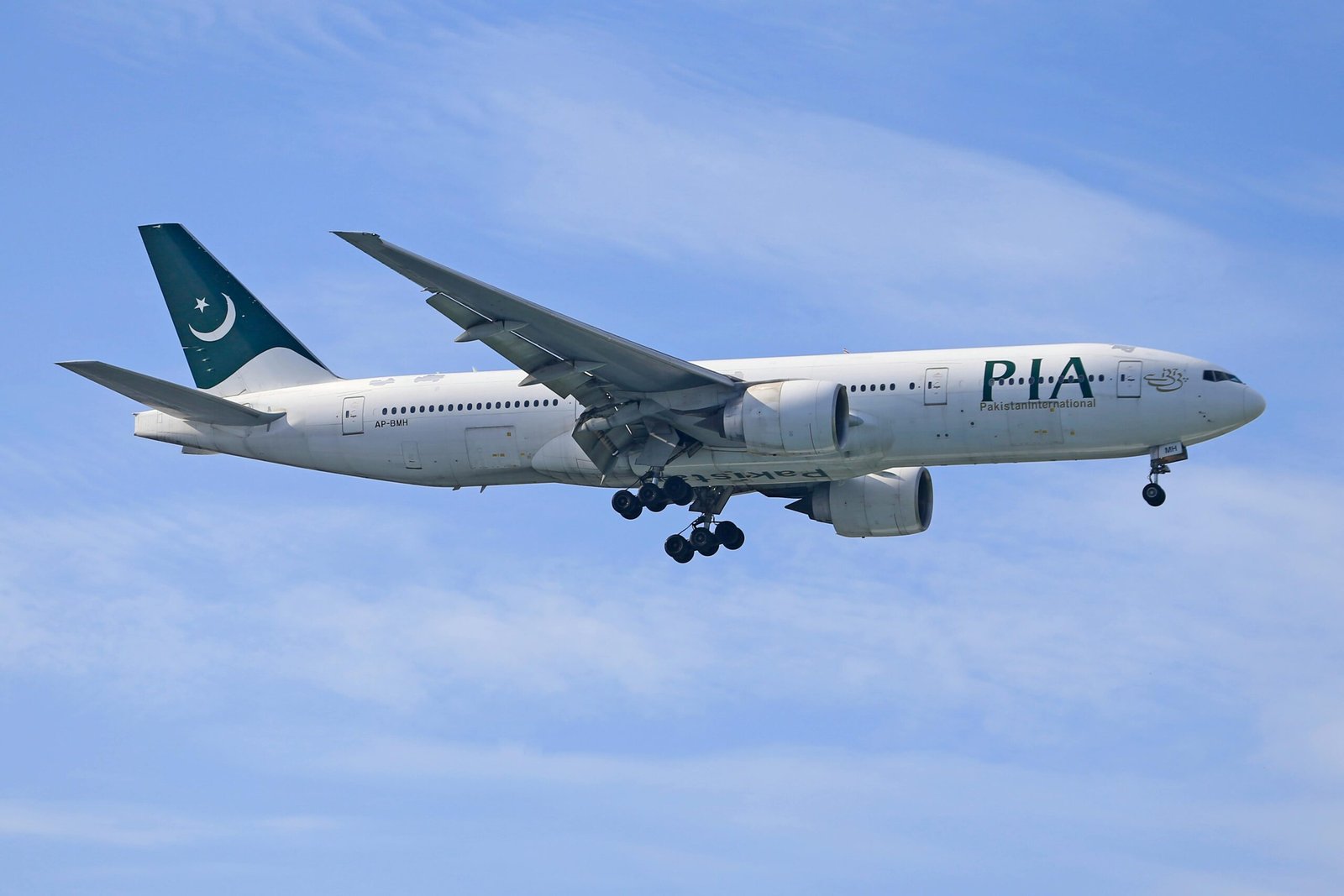 A Pakistan International Airlines Boeing 777 captured mid-flight against a clear blue sky.